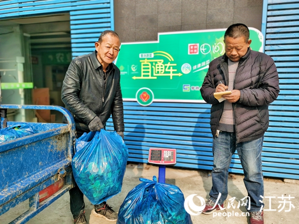 东盾村收购点负责人沈正荣（右）为村民徐建良送来的菠菜过磅记录。人民网记者 王继亮摄