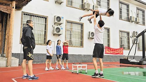 7月12日，在位于涞源的河北省跳台滑雪队训练基地内，主教练徐洪彬（左一）正在指导队员进行陆地托举模仿训练。 本报记者 赵瑞雪摄