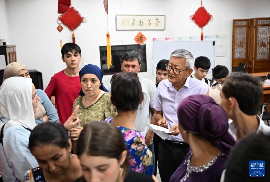 9月12日，在塔吉克斯坦首都杜尚别的国家图书馆中国厅，李建军老师（中右）在报名现场和学生家长交流。新华社记者 李任滋 摄