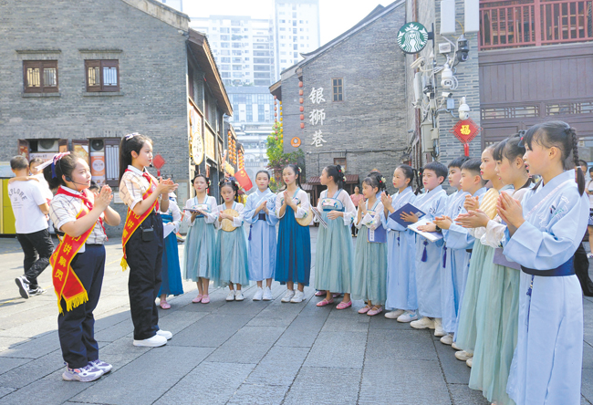 在中华大戏院门前，南宁市华强路小学的学生们齐声念童谣。记者宋延康摄