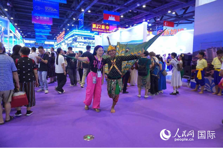 游客在“魅力之城”柬埔寨展区前与柬埔寨舞蹈演员合影。人民网 杨春燕摄