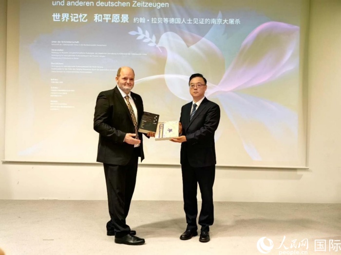 侵华日军南京大屠杀遇难同胞纪念馆馆长周峰向约翰拉贝曾外孙克里斯托夫·赖因哈特赠送纪念品。 人民网记者 郭梓云摄