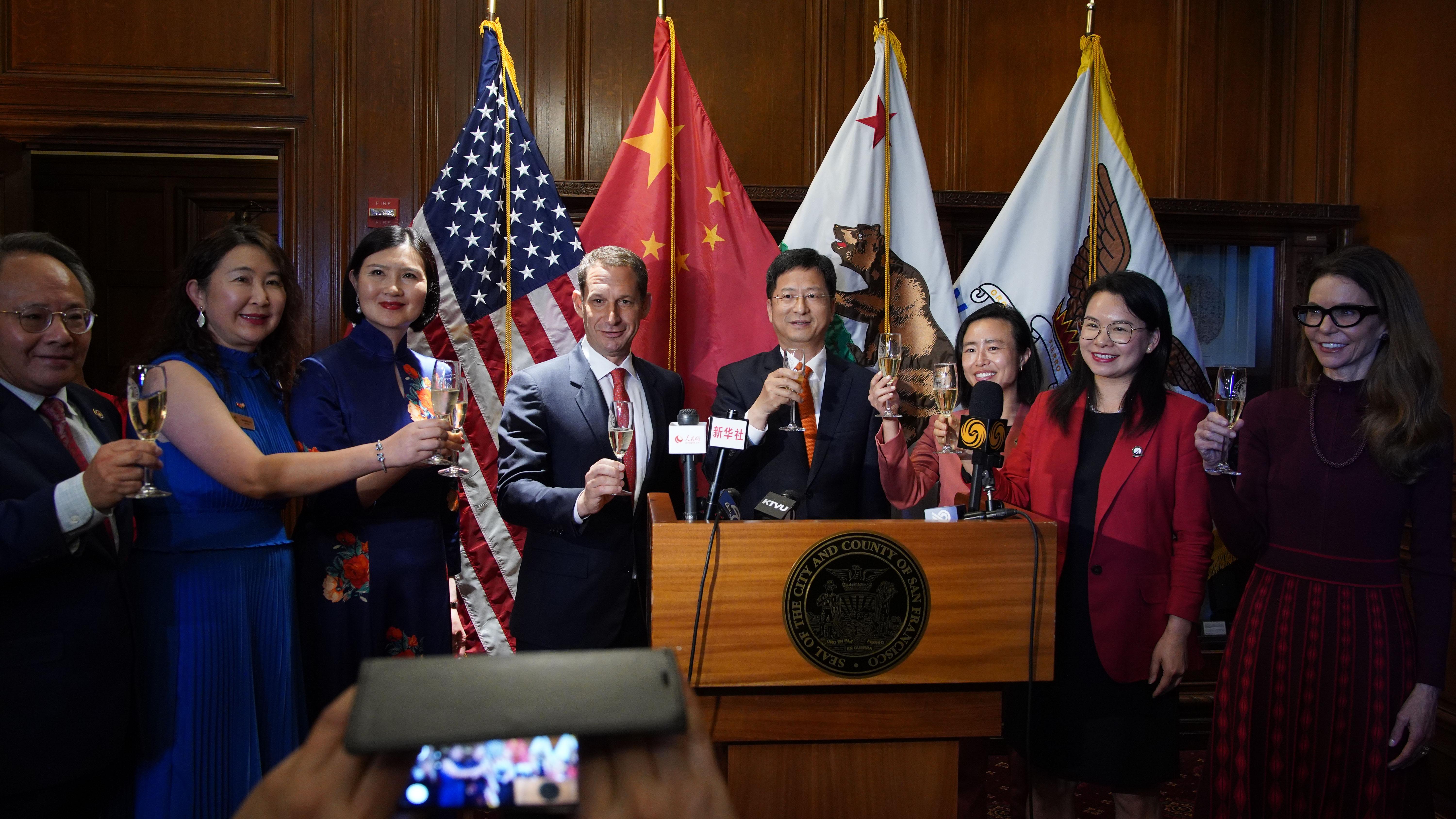 在旧金山市政厅，中国驻旧金山总领事张建敏（右），与旧金山市长丹尼尔·罗里（左中）一起举杯，与参加升旗仪式的嘉宾庆祝中华人民共和国成立 76 周年。谢为人摄