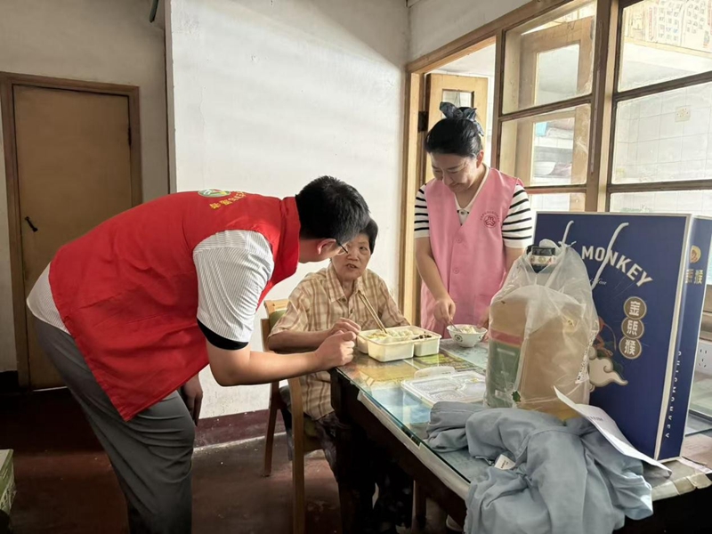 志愿者徐声凯为邵桂芬送上午餐。柏敏卿摄